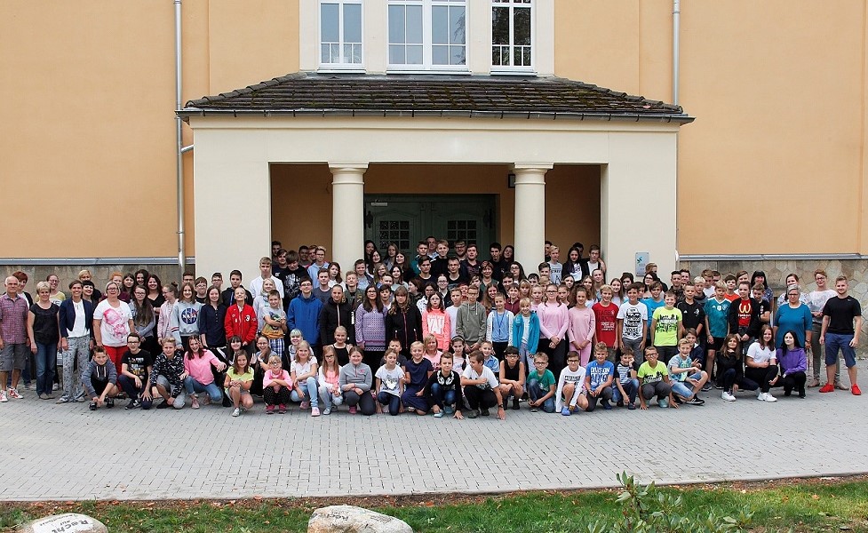 Alle Schüler und Lehrer stehen vor dem Schulgebäude.